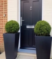 donica-wysoka-80cm-trapez-czarna-przed-wejsciem.webp